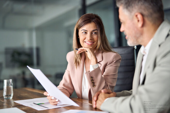 Two Business Executives Discussing Financial Papers In Office At Meeting.